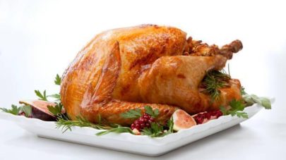 Garnished traditional roasted turkey, garnished with fresh figs, pomegranate, and herbs. On white background.